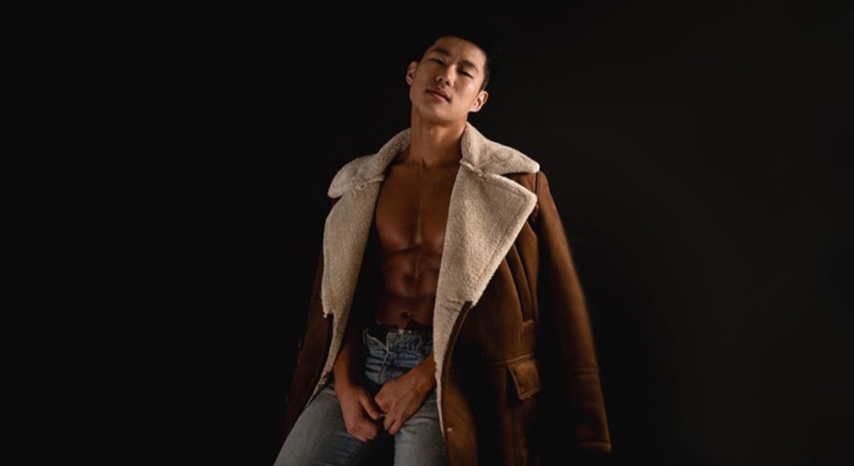 man in blue denim jeans with brown leather coat draped over shoulders