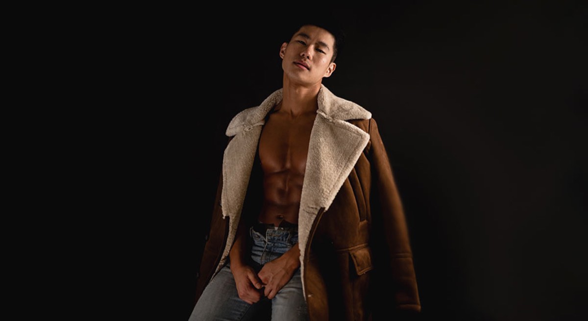 man in blue denim jeans with brown leather coat draped over shoulders
