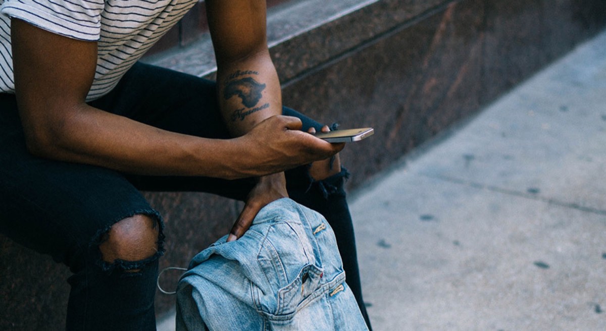 man using smartphone and holding jeans